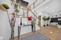 Open-concept entryway featuring a modern staircase with light wood railings and glass panels - 