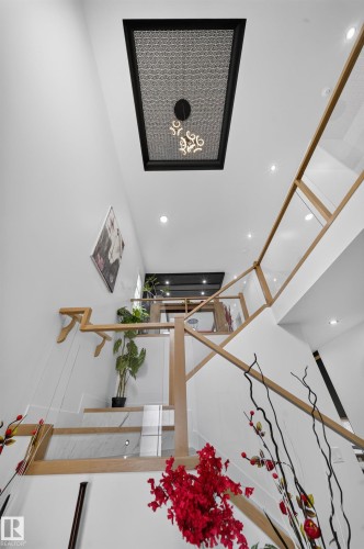 Staircase featuring wood railings and glass panels, recessed ceiling lighting, and a decorative ceiling light fixture - 626 Astoria Way, Devon, AB 