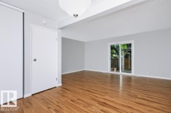 Open-concept living space featuring wood-finish flooring, light grey walls, and a white ceiling - 