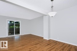 Spacious interior featuring wood-finish flooring, light gray walls, white trim, and a white ceiling with a contemporary pendant light fixture - 