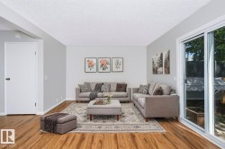 Living area featuring wood-finish flooring, light gray wall paint, and a textured white ceiling - 