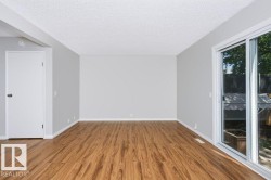 Spacious room featuring light gray walls, wood-finish flooring, and white baseboards - 