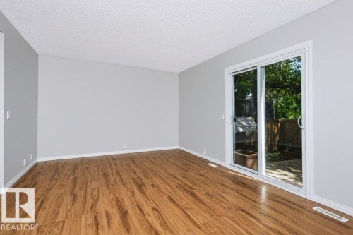 Spacious room featuring wood-finish flooring, light gray walls, and white trim - 24 14511 52 Street, Edmonton, AB 