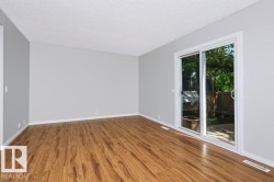 Spacious room featuring wood-finish flooring, light gray walls, and white trim - 