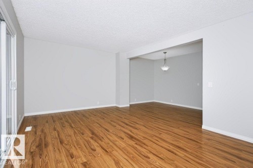 Expansive room featuring wood-finish flooring, light gray walls, and white trim - 24 14511 52 Street, Edmonton, AB 