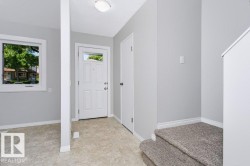 Entryway featuring a paneled door with transom window, light gray walls, and textured flooring - 