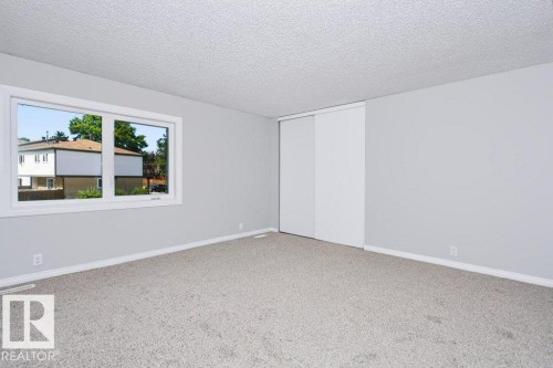 Spacious room featuring light gray walls, textured ceiling, and light-colored carpet - 24 14511 52 Street, Edmonton, AB 