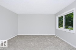 Interior room featuring light gray wall paint, gray carpet flooring, white baseboards, and a white-framed window - 
