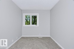 Bright room with gray textured carpeting, light gray painted walls, a white-framed window, and white baseboards - 