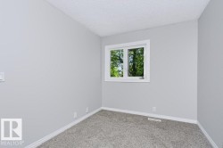 Light gray painted walls with white trim and a single window offering a view of greenery - 