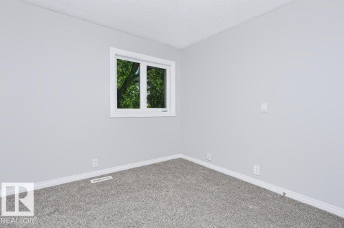 Room featuring light gray wall paint, gray carpet flooring, white baseboards, and a white-framed window - 24 14511 52 Street, Edmonton, AB 