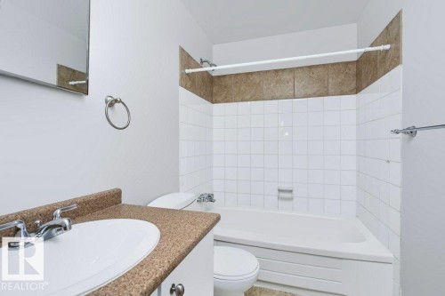 Bathroom featuring a white vanity with an integrated sink, a speckled countertop, and chrome fixtures - 24 14511 52 Street, Edmonton, AB 