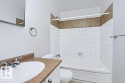 Bathroom featuring a white vanity with an integrated sink, a speckled countertop, and chrome fixtures - 
