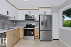 Contemporary kitchen featuring white upper cabinetry, wood-finish lower cabinetry, and stainless steel appliances - 