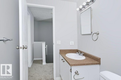 Bathroom vanity featuring a white oval sink, chrome faucet, and a speckled countertop - 24 14511 52 Street, Edmonton, AB 