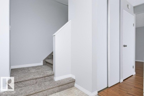Carpeted staircase with white trim, light gray wall finishes, and solid white doors - 24 14511 52 Street, Edmonton, AB 