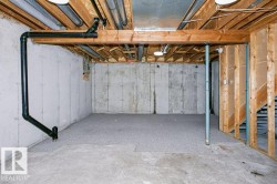 Unfinished basement with concrete walls, exposed ceiling joists, and a partial subfloor - 