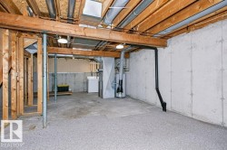 Lower level space featuring exposed ceiling joists, concrete walls, a water heater, and a washer - 