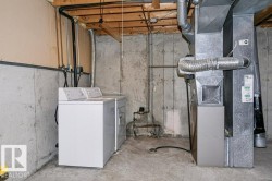 Utility area featuring a concrete floor, concrete foundation walls, exposed ceiling joists, and a forced-air furnace with visible ductwork - 