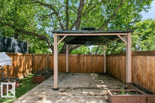 Expansive outdoor patio featuring a built-in gazebo with a dark roof, surrounded by a wood privacy fence - 24 14511 52 Street, Edmonton, AB 