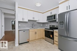Contemporary kitchen featuring two-tone cabinetry, stainless steel appliances, a tile backsplash, and a built-in microwave - 