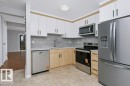 Contemporary kitchen featuring two-tone cabinetry, stainless steel appliances, a tile backsplash, and a built-in microwave - 24 14511 52 Street, Edmonton, AB 