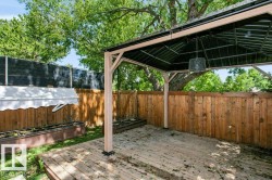 Outdoor wood deck featuring a covered gazebo structure with a metal roof and a hanging light fixture - 
