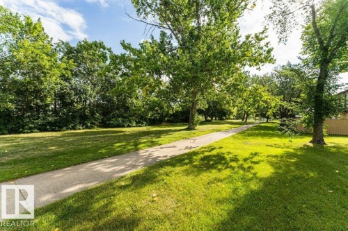 Expansive green space featuring a paved pathway, mature trees, and natural landscaping - 24 14511 52 Street, Edmonton, AB 