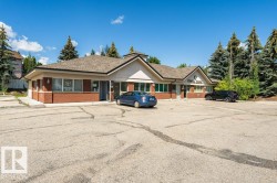 Commercial building featuring a large paved parking area, brick lower facade, multiple window units, and a shingled roof - 