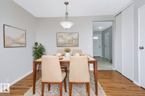 Dining area featuring wood-finish flooring and a central pendant light fixture - 24 14511 52 Street, Edmonton, AB 