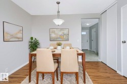 Dining area featuring wood-finish flooring and a central pendant light fixture - 