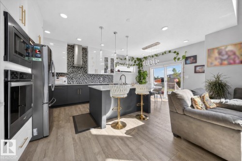 Open-concept kitchen featuring an island with a light-toned countertop, stainless steel appliances, a mosaic tile backsplash, and recessed lighting - 1927 18 Street, Edmonton, AB 