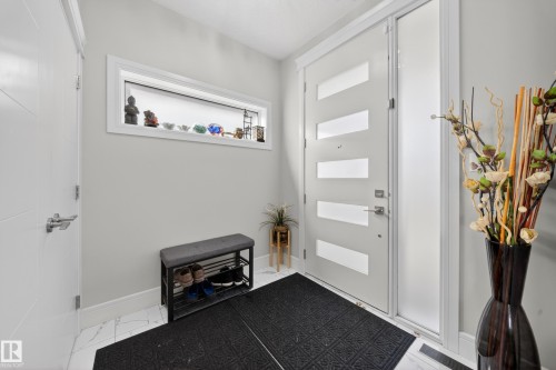 Entryway featuring a contemporary white door with frosted glass panels, a frosted glass sidelight, and marble-look tile flooring - 1927 18 Street, Edmonton, AB 