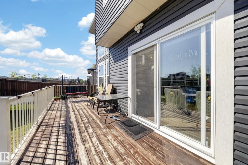 Exterior deck with white railing, featuring a sliding glass patio door and dark horizontal siding - 1927 18 Street, Edmonton, AB 