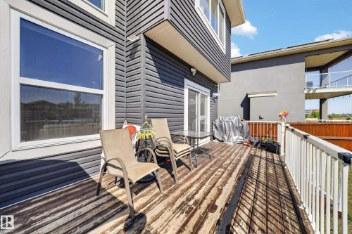 Rear wood-finish deck with white railing, featuring dark gray siding and a sliding glass door - 1927 18 Street, Edmonton, AB 