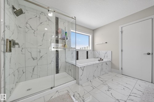 Bathroom featuring a tiled shower with sliding glass doors, a built-in soaking tub, and a window - 1927 18 Street, Edmonton, AB 