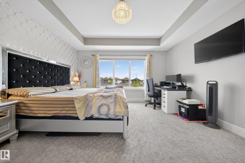 Spacious room featuring tray ceilings, light gray carpeting, and a decorative accent wall - 1927 18 Street, Edmonton, AB 