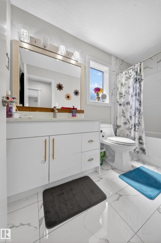 White vanity with gold-tone hardware, a large framed mirror, and a four-bulb fixture - 1927 18 Street, Edmonton, AB 