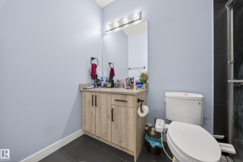 Bathroom featuring a wood-finish vanity with a light-toned countertop, a rectangular mirror, and an overhead light fixture - 1927 18 Street, Edmonton, AB 