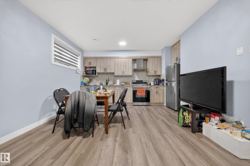 Open-concept kitchen and dining area featuring wood-finish flooring, light blue wall paint, and recessed lighting - 1927 18 Street, Edmonton, AB 