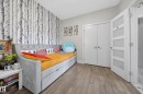 Room featuring wood-finish flooring, a feature wall with patterned wallpaper, and a white bi-fold closet - 1927 18 Street, Edmonton, AB 