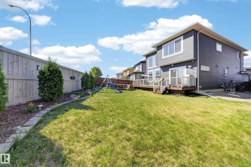 Modern exterior with horizontal siding, an expansive wood deck, and a grass lawn - 1927 18 Street, Edmonton, AB 