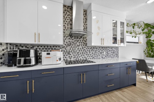 Kitchen featuring sleek white upper cabinetry and contrasting navy lower cabinetry, each with gold-tone hardware - 1927 18 Street, Edmonton, AB 
