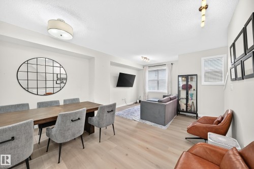 Open-concept living space with light wood-finish flooring, recessed lighting, and ample natural light from multiple windows - 118 655 Watt Boulevard Sw, Edmonton, AB 