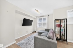 Living area featuring light wood-finish flooring, neutral wall paint, track lighting, and window with blinds - 