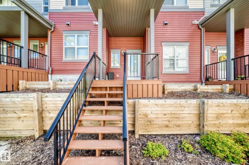 Exterior townhouse facade with red horizontal siding and white trim windows - 118 655 Watt Boulevard Sw, Edmonton, AB 