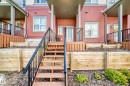 Exterior townhouse facade with red horizontal siding and white trim windows - 118 655 Watt Boulevard Sw, Edmonton, AB 