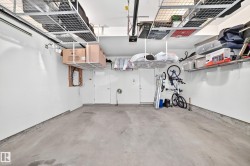 Spacious garage with overhead storage racks, concrete flooring, and white walls - 