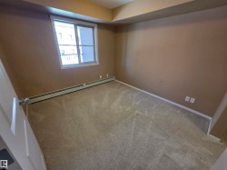 Carpeted interior space featuring a window with white trim, baseboard heating, neutral wall paint, and white baseboards - 