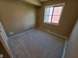 Carpeted room with a double-pane window, baseboard heating, and neutral wall tones - 